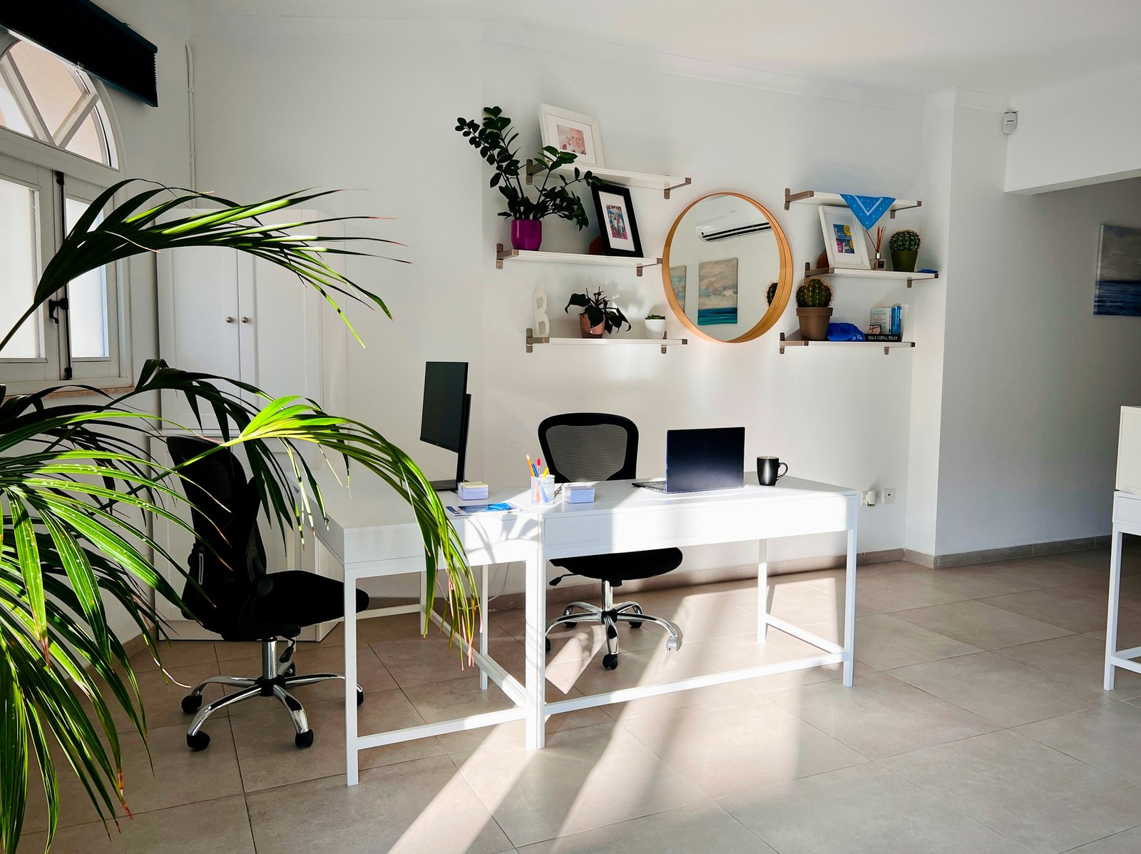Minimal creative workspace with plants, natural light, and a clean desk.